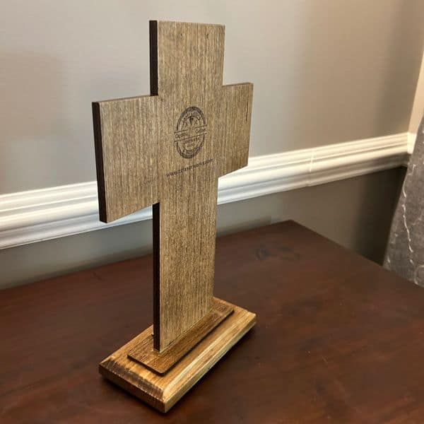 Untitled wooden cross with engraved logo on a table, used for religious or decorative purposes.