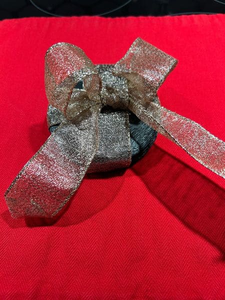Shiny silver ribbon bow on a red tablecloth for holiday or celebration decor.